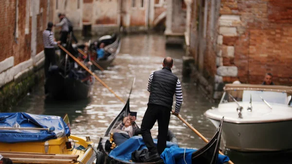 Водный канал Венеции - мужчины гребут на лодке вдоль реки — стоковое фото
