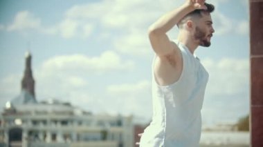 Şehrin bir arka plan üzerinde standında dans beyaz gömlek dövmeler ile genç şık adam