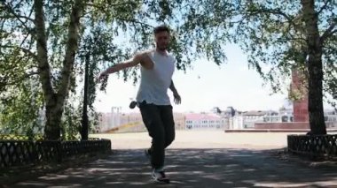 Parkta dövmeler freestyle dans ile Genç çekici adam - arka planda binalar