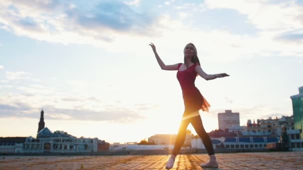 Молодая привлекательная балерина в пуантах эстетически и грациозно исполняет балетный танец на площади города — стоковое видео