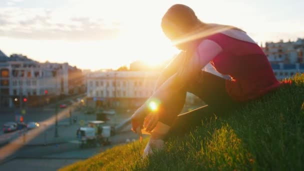 Ung ballerina fäster bogserbåten på hennes Pointe sitter på en grön kulle i mitten av staden. — Stockvideo