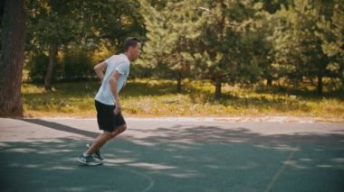 Genç adam arkadaşları ile spor sahasında basketbol oynarken - top sürme, rakiplerinden kaçınarak - gol vurdu