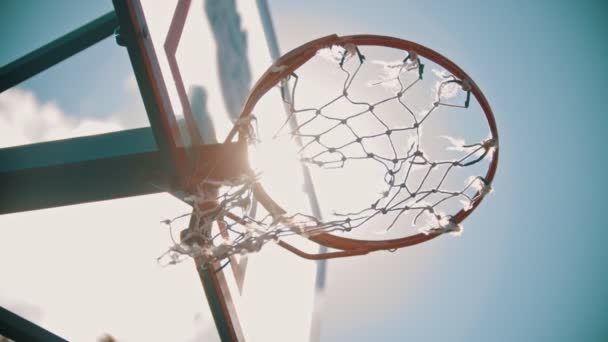 Баскетбольне кільце. М'яч потрапляє у ціль. Яскраве сонячне світло — стокове відео