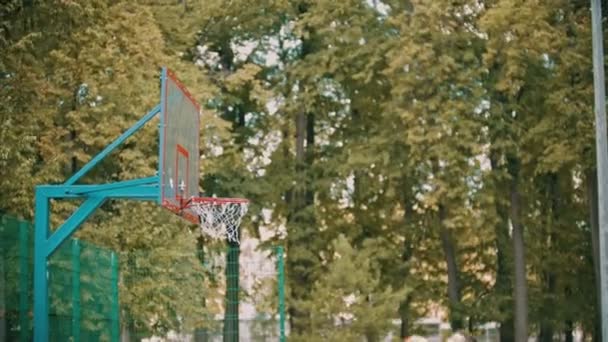 Trening koszykówki na zewnątrz-młody człowiek skoki i rzucanie piłki i dostaje w celu — Wideo stockowe