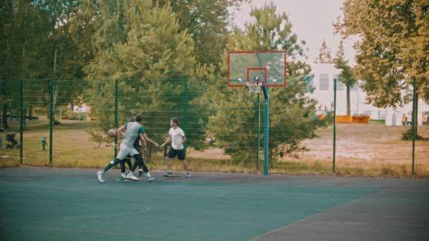 Quatre jeunes amis qui jouent au basket-ball sur le terrain de sport - la balle dans la cible — Video