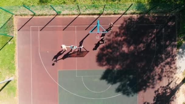 Hombres jóvenes en forma jugando baloncesto en la cancha al aire libre — Vídeo de stock