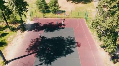 Dört genç adam açık havada sahada basketbol oynuyor