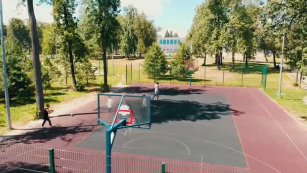 Čtyři mladí muži hrajou basketbal na sportovní půdě v přírodě. — Stock video