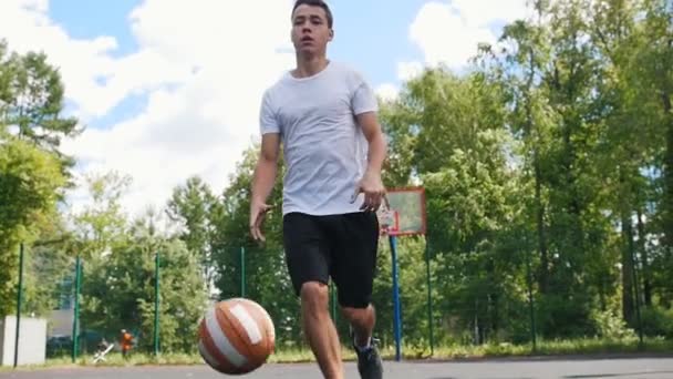 Genç adam arkadaşı ve top sürme ile açık havada basketbol oynuyor — Stok video