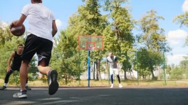 Genç adam arkadaşı ile açık havada basketbol oynarken, top sürme ve gol