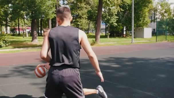 Tři sportovec hrají basketbal na hřišti v přírodě-jeden muž hází míč do koše a skóruje — Stock video