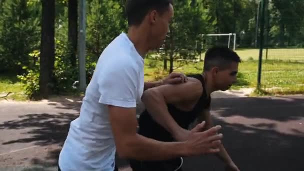 Due sportivi che giocano a basket sul campo all'aperto, uno sportivo che sbava e manca oltre il cesto — Video Stock