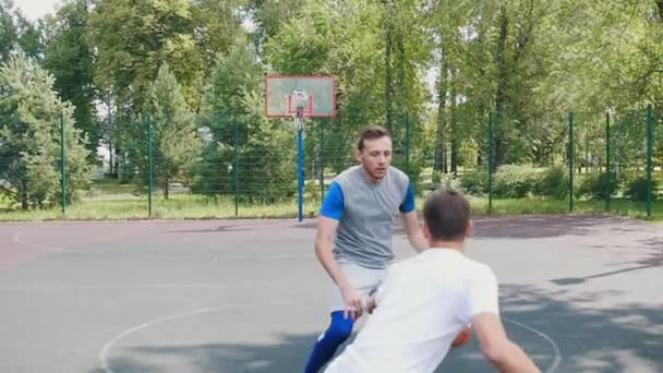 ハンサムなスポーツマンは、2人の友人とバスケットボールをプレイし、ボールをドリブルし、バスケットに入れて — ストック動画