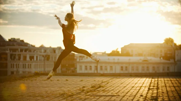 Ung graciös kvinna ballerina dansa och hoppa på taket-ljus solnedgång — Stockfoto