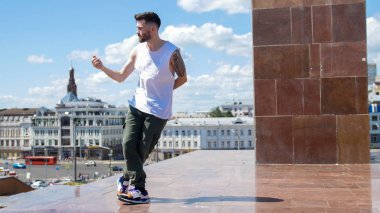 Standda dövmeler freestyle dans ile genç şık adam - arka planda şehrin merkezi