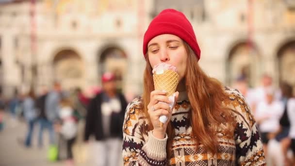 Νεαρή γυναίκα που περπατάει στην πλατεία της πόλης και τρώει το παγωτό — Αρχείο Βίντεο