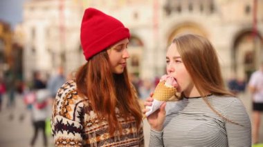 Şehir meydanında yürüyen ve dondurma yiyen iki kadın