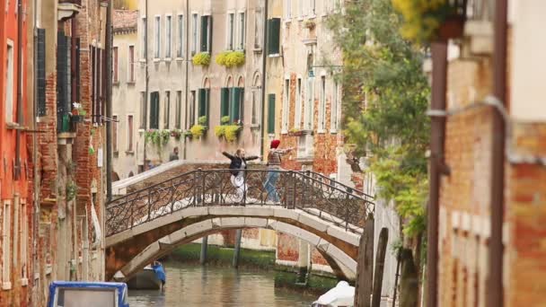 Två unga kvinnor Standig på bron mellan gatorna i Venedig-hoppning och ha kul — Stockvideo