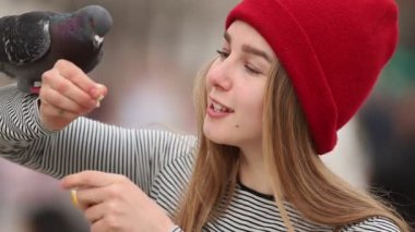 Açık havada güvercini besleyen genç kadın