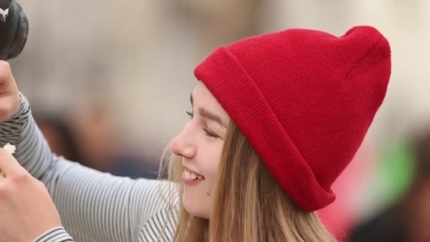 Jovem sorrindo mulher em chapéu vermelho alimentando pombas na rua — Vídeo de Stock