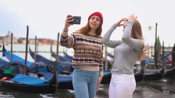 Dos mujeres jóvenes en el paseo marítimo con barcos hablando y tomando selfie — Vídeo de stock