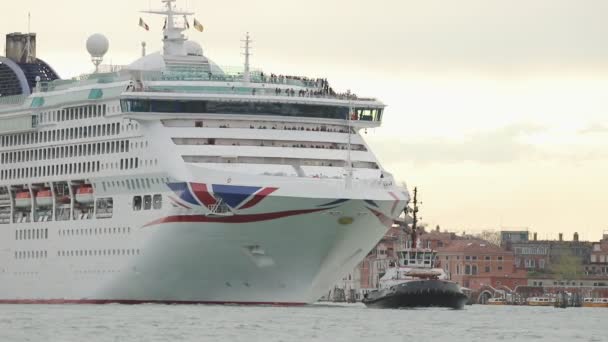 Een kleine boot trekt een enorme cruiseschip langs de rivier in Venetië — Stockvideo