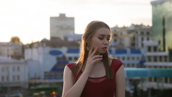 Een jonge geïnspireerde vrouw in rode jurk staande op het dak en poseren voor de camera — Stockfoto