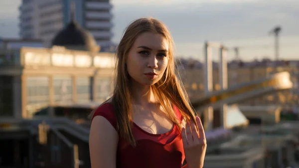 Una giovane donna ispirata in abito rosso in piedi sul tetto e in posa per la fotocamera al tramonto — Foto Stock