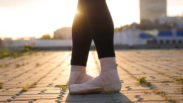 Benen van jonge vrouw ballerina staande in de klassieke stand op de volle voeten-zonsondergang — Stockfoto