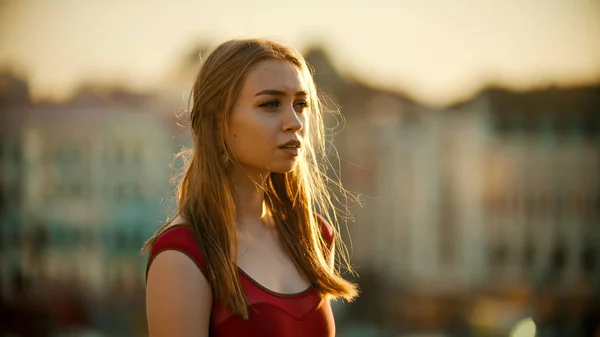 Молодая вдохновленная женщина в красном платье, стоящая на крыше - яркий закат — стоковое фото