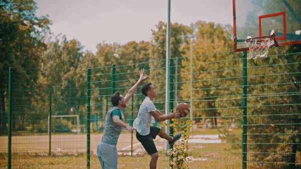 Män som spelar basket på idrottsplats utomhus — Stockfoto