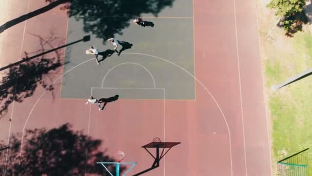 Четверо юношей играют в баскетбол на спортивной площадке на улице — стоковое видео