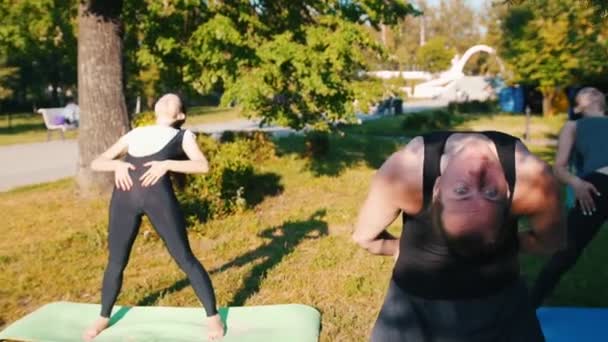 Due giovani donne che fanno yoga nel parco con il loro istruttore appoggiandosi indietro — Video Stock