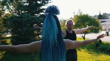 Eğitmenleri ile parkta yoga yapan iki genç kadın - ellerini kaldırın - mavi dreadlocks ile bir kadın
