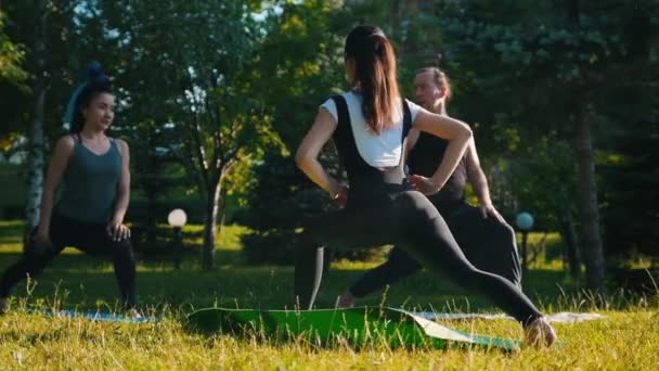 Dos mujeres jóvenes haciendo ejercicio en el parque con su entrenador - realizando ejercicios en las piernas - estiramiento — Vídeos de Stock