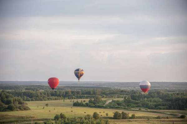 18-07-2019 ペレスラヴリ・ザレスキー, ロシア: 熱技術を使用してフィールド上を飛ぶ3つの異なるカラフルな気球. — ストック写真