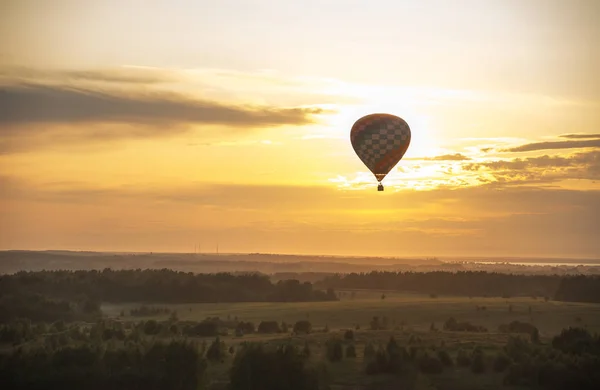 An air balloon flying over the field using heat technology - bright sunset — Stock Photo, Image