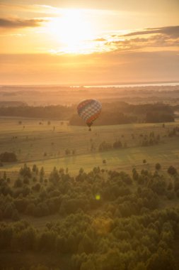 Orman ve alan üzerinde uçan bir hava balonu - parlak gün batımı
