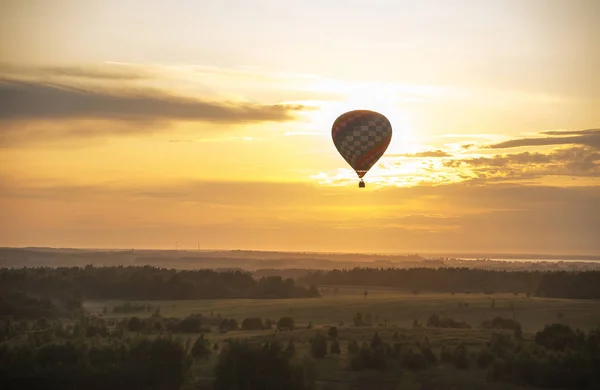 Um balão de ar voando sobre o campo usando tecnologia de calor por do sol — Fotografia de Stock