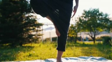 Yoga asana yapan ve gün ışığında parkta gülümseyen bir adam