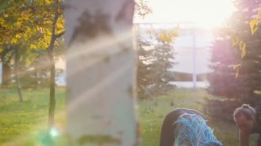 Güneş ışığında parkta eğitmen ile yoga egzersizleri yapan iki genç kadın - Bir kadın uzun mavi dreadlocks var