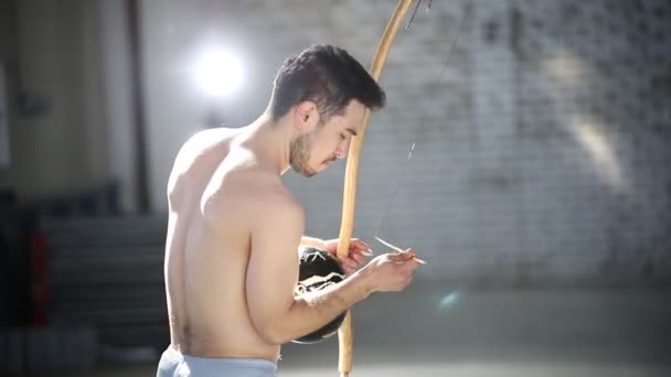 Молодий привабливий чоловік готує національний бразильський інструмент Бермбоу — стокове відео