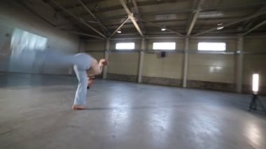 Beton zemin ve tuğla duvarlar ile odada zor capoeira elemanları yapıyor bir adam