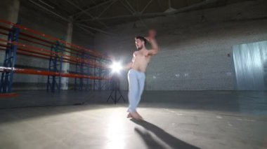 Bir adam capoeira elemanları yapıyor - bir cartwheel - beton zemin, tuğla duvarlar ve parlak ışık ile odada