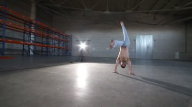 Bir adam capoeira elemanları yapıyor - bir cartwheel - beton zemin ve tuğla duvarlar ile odada