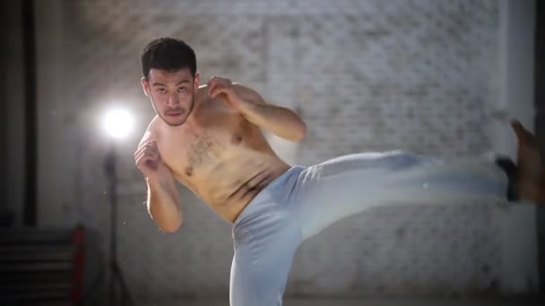 Young athletic man doing capoeira exercises - turning around and lifting leg - then he repeats moves — Stock Video