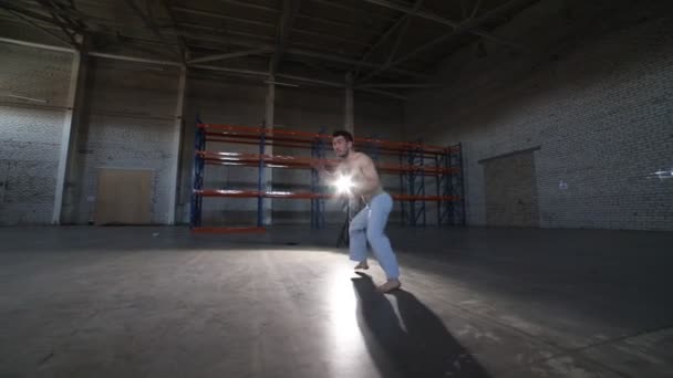 En atletisk man gör olika Capoeira element-kullerbytta över huvudet utan händer-i rummet med betonggolv och tegelväggar — Stockvideo