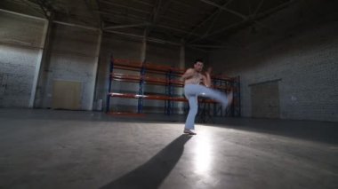 Bir atletik adam capoeira elemanları yapıyor - atlar, döner ve somersaults - beton zemin ve tuğla duvarlar ile odada