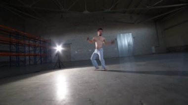 Bir atletik adam zor capoeira elemanları yapıyor - elleri olmadan başının üzerinde somersault - beton zemin ve tuğla duvarlar ile odada