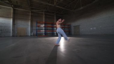Bir adam capoeira elemanları yapıyor - elleri olmadan başının üzerinde takla - beton zemin ve tuğla duvarlar ile odada